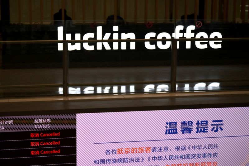 FILE PHOTO: Sign of Luckin Coffee is seen behind an information board showing cancelled flights, at the Beijing Daxing International Airport, as the country is hit by an outbreak of the novel coronavirus, in Beijing