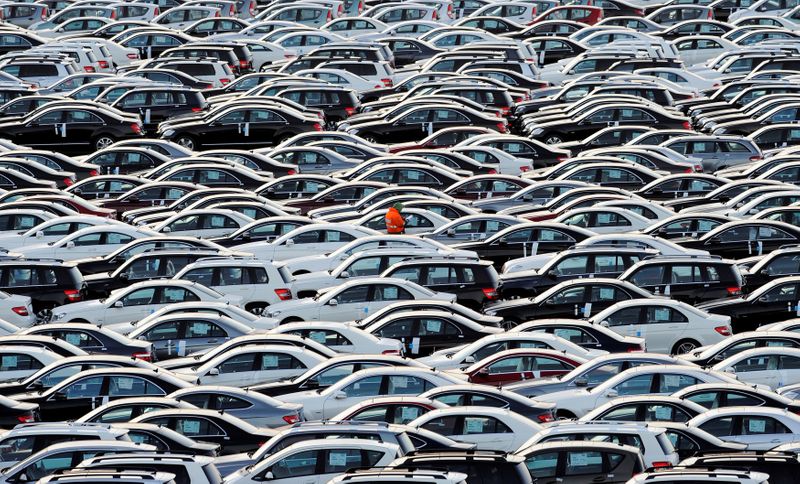 FILE PHOTO: A worker walks along rows of Mercedes cars at a shipping terminal in the harbour of the town of Bremerhaven