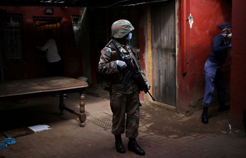 FILE PHOTO: A soldier and a member of the South African police service search a house