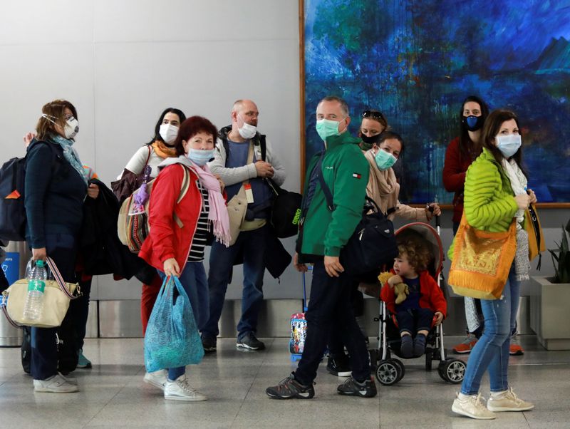 FILE PHOTO: Passengers wearing protective masks arrive to collect their luggage inside an airport following an outbreak of the coronavirus disease (COVID-19), in New Delhi