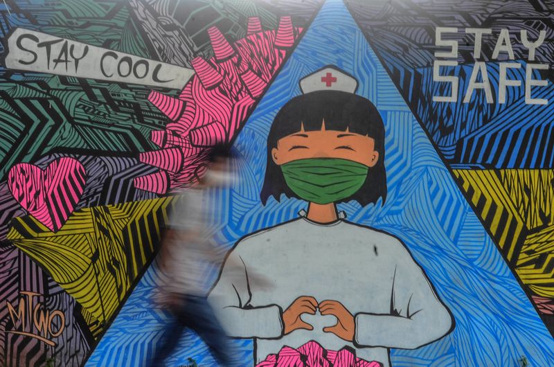 FILE PHOTO: Person walks near a mural depicting a nurse to support healthcare workers in the frontline amid the spread of coronavirus disease (COVID-19) outbreak in Ciamis