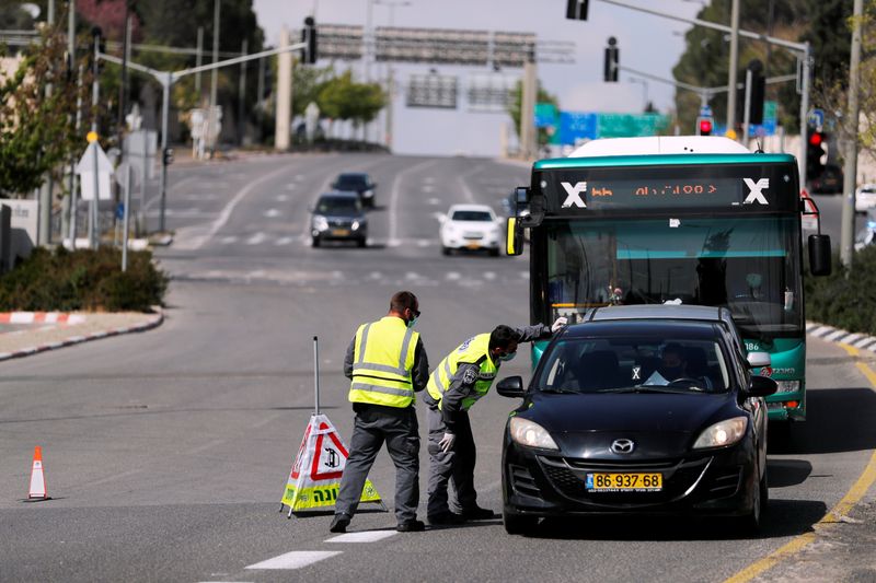 Israeli police check a driver in a car on a roadblock in a main road in Jerusalem as they try to contain the spread of the coronavirus disease (COVID-19) from the densely populated neighborhoods where the infection rate is high