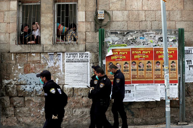 FILE PHOTO: Israeli policemen wearing masks talk to residents from their window as they enforce government restrictions placed to curb the spread of the coronavirus disease (COVID-19) in Jerusalem