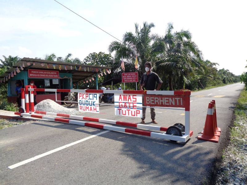 FILE PHOTO: Local villager Arifin Anak Mingok stands behind a roadblock set up in Busut Baru village in Hulu Langat, Selangor State, Malaysia