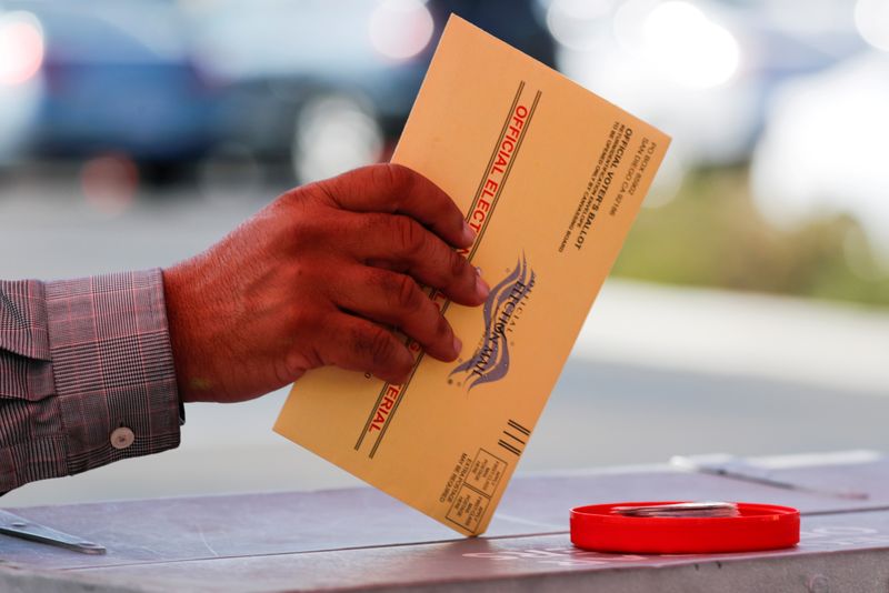 FILE PHOTO: An election worker places a mail-in ballot into an election box at a drive-through drop off location at the Registrar of Voters in San Diego, California