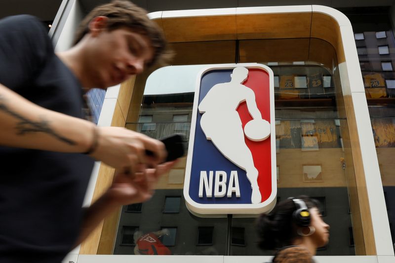 FILE PHOTO: The NBA logo is displayed as people pass by the NBA Store in New York