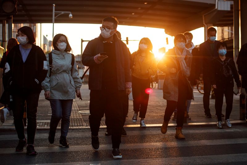 People wear protective masks as they leave work during evening rush hour in Beijing as the spread of the novel coronavirus disease (COVID-19) continues