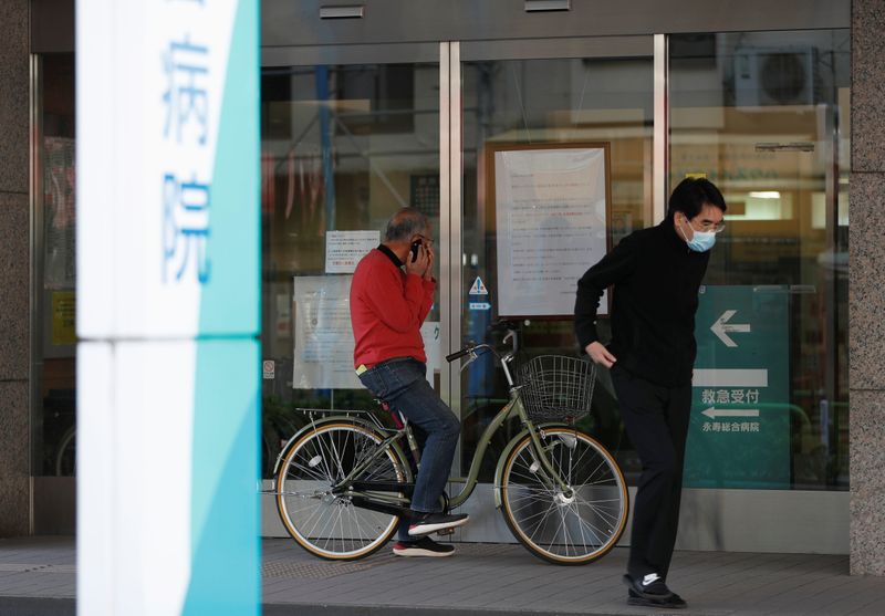 Men wearing protective face masks, following an outbreak of the coronavirus disease, look at closed notice at the entrance of Eiju General Hospital in Tokyo