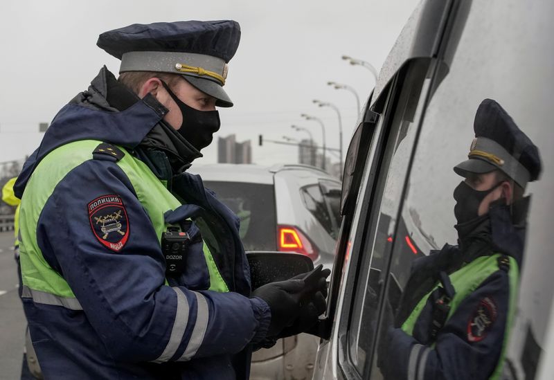 A traffic police officer wearing a protective mask uses a mobile device while checking a pass to travel, at a checkpoint set up after Moscow authorities tightened up measures to prevent the spread of the coronavirus disease (COVID-19), in Moscow