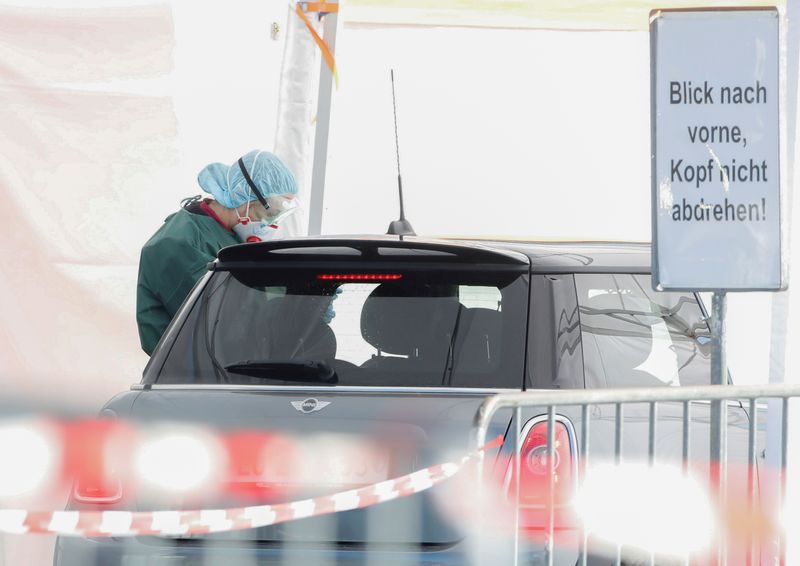 FILE PHOTO: Health worker takes a test from a person in a car at a drive-in test center in Luzern