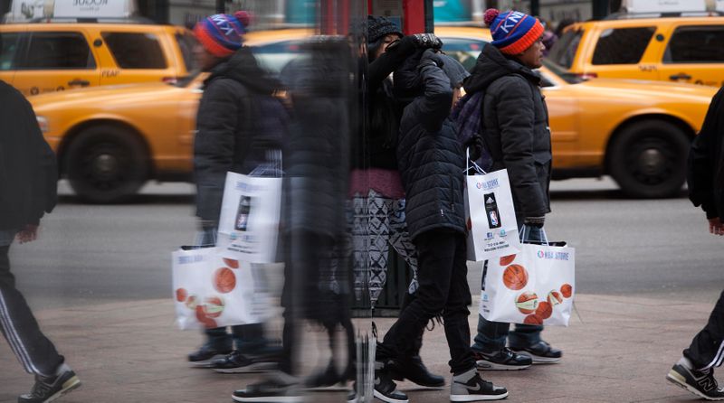 People are reflected in a mirror as they shop during Black Friday sales in New York