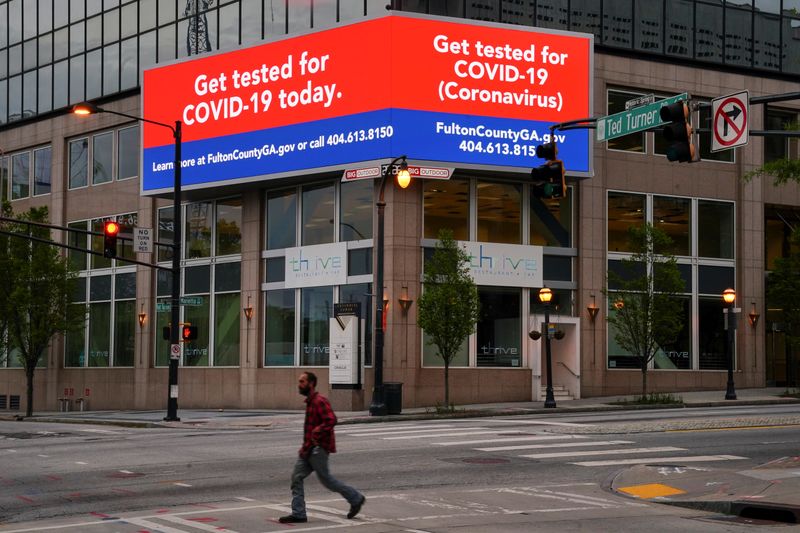 A man walks in front of a sign encouraging the public to get tested for COVID-19, days before the phased reopening of businesses from coronavirus disease rules in Atlanta