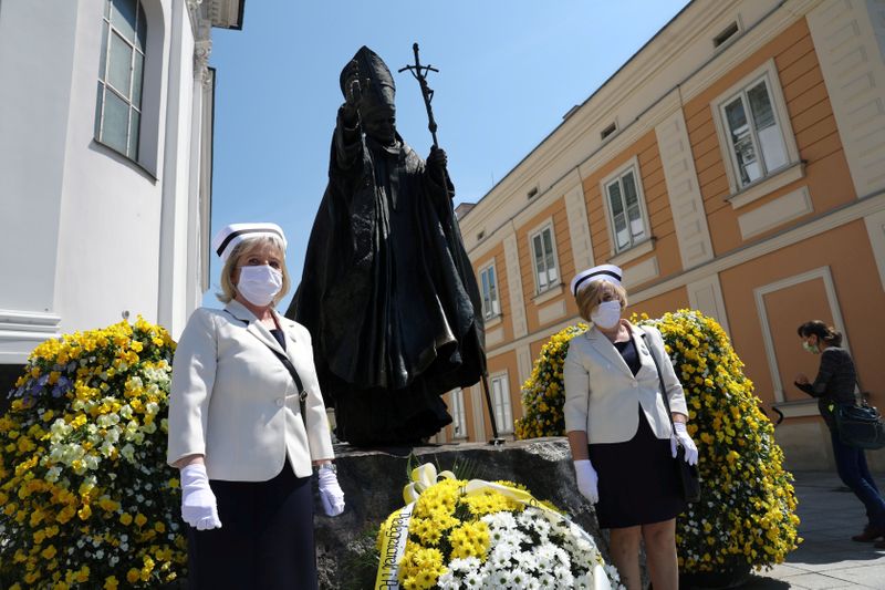 Nurses in protective masks attend a ceremony to commemorate the 100th anniversary of the birth of late Pope John Paul II next to his monument in Wadowice
