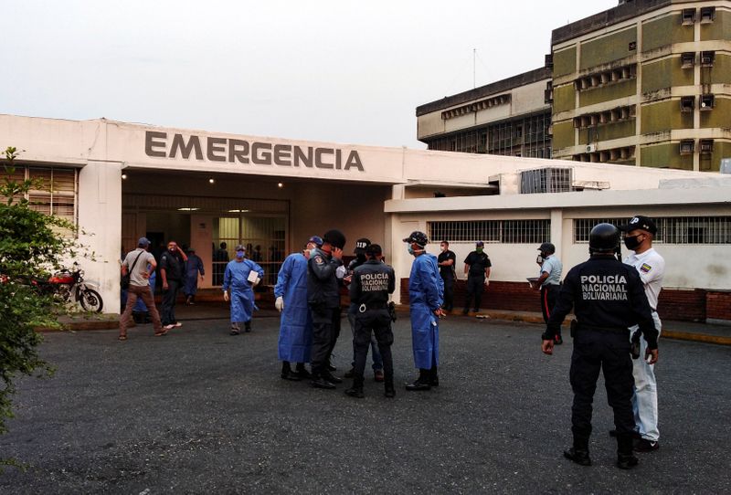 Healthcare workers and members of the Bolivarian national police wait for the arrival of prisoners outside a hospital after a riot erupted inside a prison in Guanare