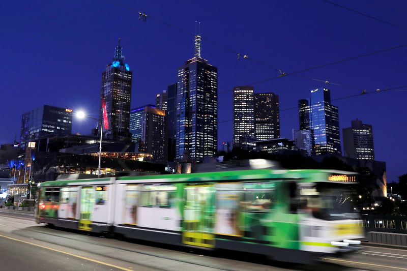 The city skyline is seen as a tram crosses the Princes Bridge at dusk in Melbourne, Victoria, Australia