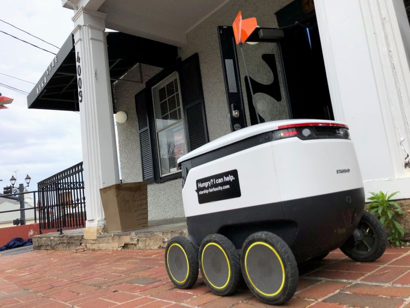 A Starship delivery robot waits outside a bar for orders to come in