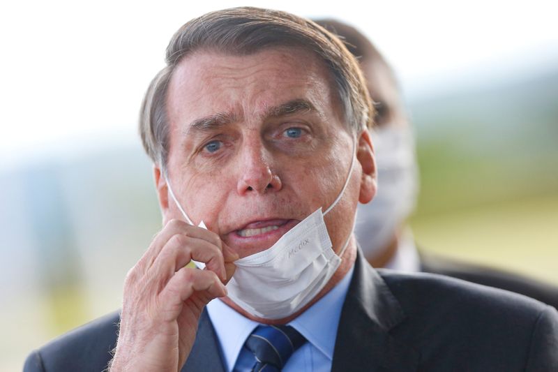 Brazil's President Jair Bolsonaro adjusts his mask as he leaves Alvorada Palace, amid the coronavirus disease (COVID-19) outbreak in Brasilia