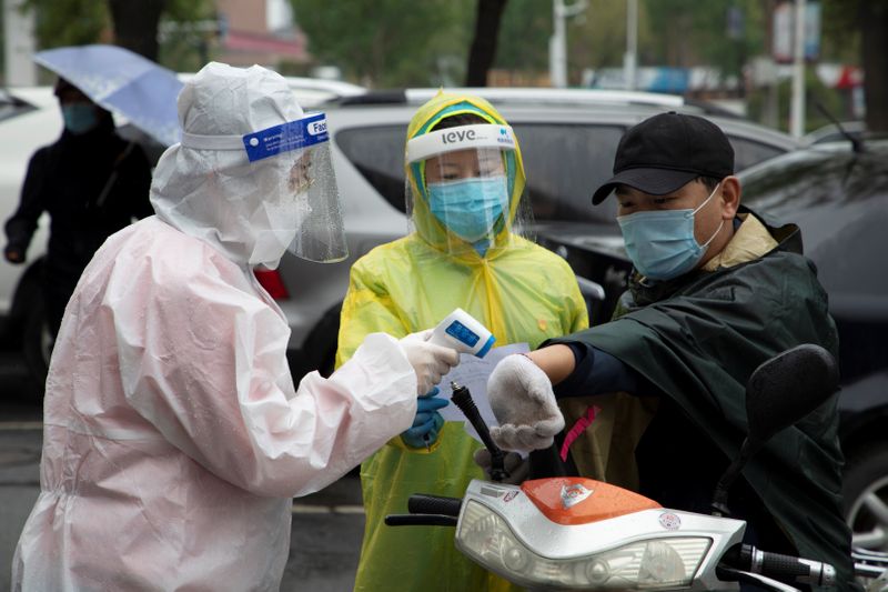 FILE PHOTO: Volunteers measure the body temperature of a man in Jilin