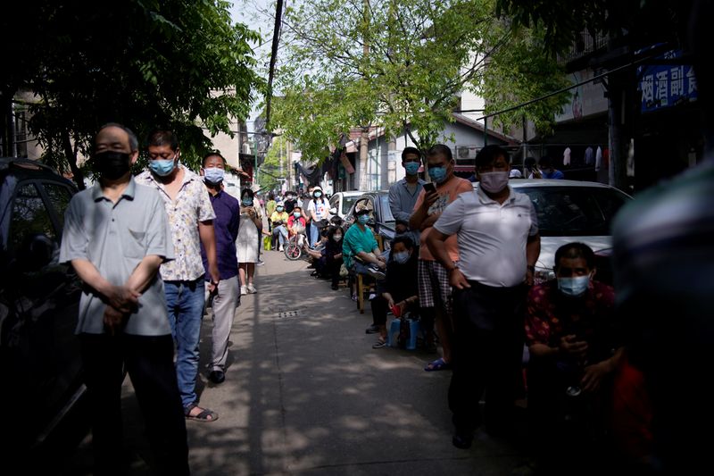 Residents wearing face masks line up for nucleic acid testings at a residential compound in Wuhan