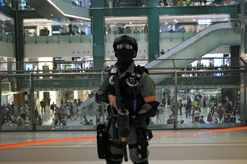 A riot police officer holds a pepper spray projectile as he disperse anti-government protesters from a shopping mall during a rally, in Hong Kong