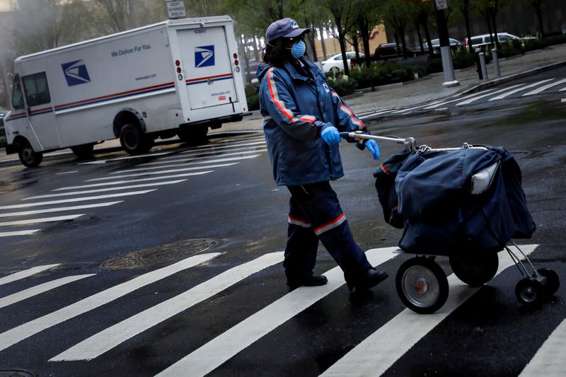 FILE PHOTO: A United States Postal Service (USPS) worker works in the rain in Manhattan during outbreak of coronavirus disease (COVID-19) in New York