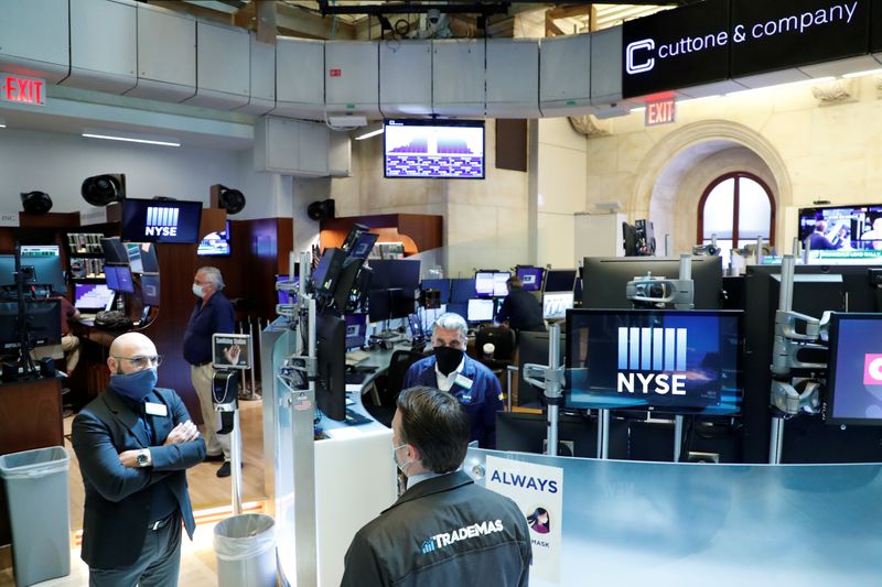 Traders wearing masks work, on the first day of in person trading since the closure during the outbreak of the coronavirus disease (COVID-19) on the floor at the NYSE in New York