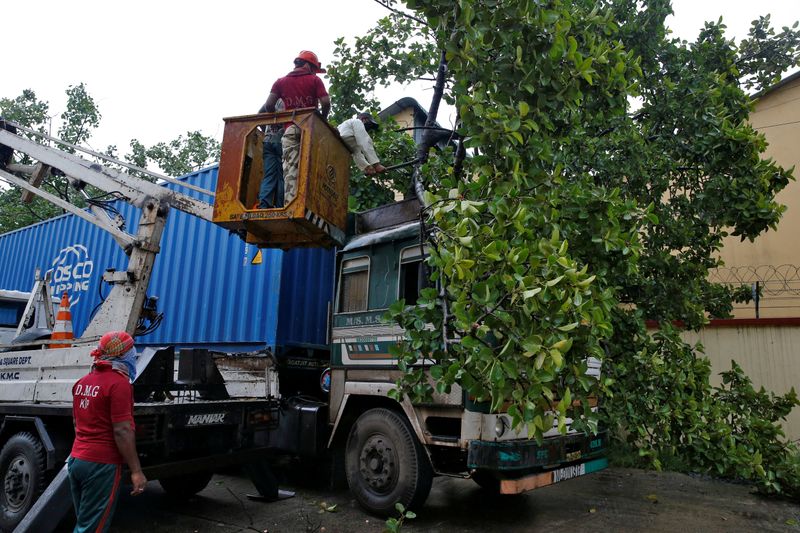 Rescue workers cut fallen tree branches after heavy winds caused by Cyclone Amphan, in Kolkata