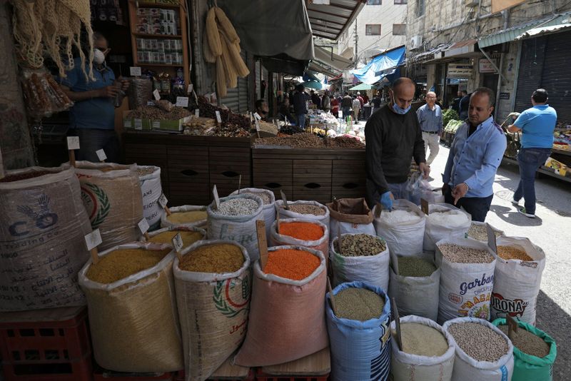 FILE PHOTO: A vendor wearing a protective face mask serves customers at his shop, ahead of the Muslim holy month of Ramadan in Amman