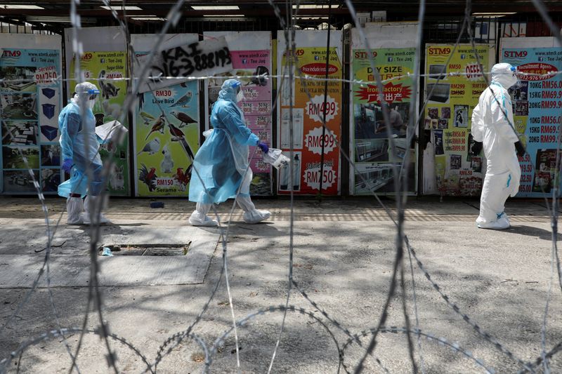 FILE PHOTO: Medical workers wearing protective suits pass by barbed wire at the red zone under enhanced lockdown, amid the coronavirus disease (COVID-19) outbreak, in Petaling Jaya