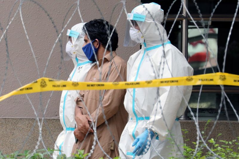 Police officers wearing protective suits pick up an illegal immigrant from an apartment under enhanced lockdown, during the movement control order due to the outbreak of the coronavirus disease (COVID-19), in Kuala Lumpur