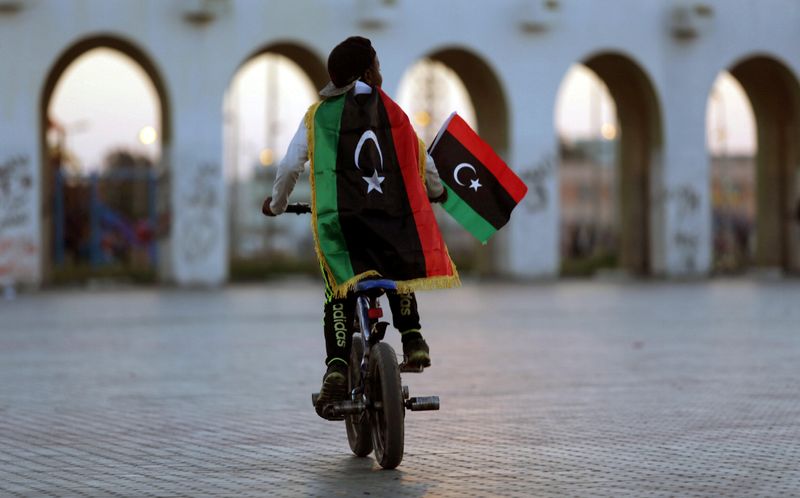 FILE PHOTO: A boy wearing a Libyan flag takes part in a celebration marking the sixth anniversary of the Libyan revolution, in Benghazi