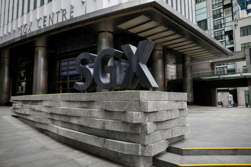 FILE PHOTO: A man wearing a protective face mask walks past the Singapore Exchange