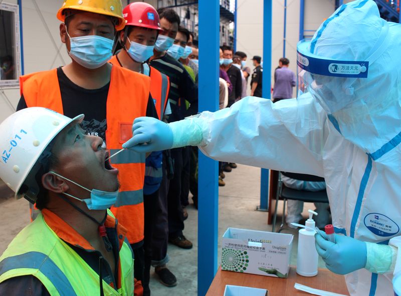 Medical worker collects swabs from construction workers for nucleic acid tests in Beijing