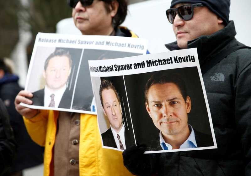 FILE PHOTO: People hold signs calling for China to release Canadian detainees Spavor and Kovrig during an extradition hearing for Huawei Technologies Chief Financial Officer Meng Wanzhou at the B.C. Supreme Court in Vancouver