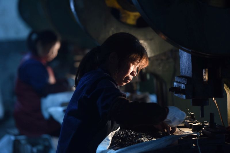 Employees work on a production line manufacturing metal parts for furniture at a factory in Hangzhou