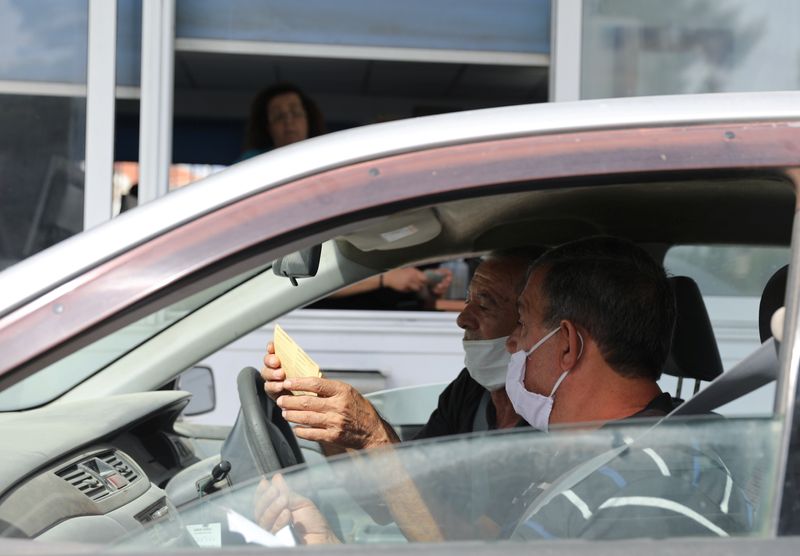 Turkish Cypriots wearing face masks look for their documents as they cross Ayios Dhometios checkpoint in Nicosia