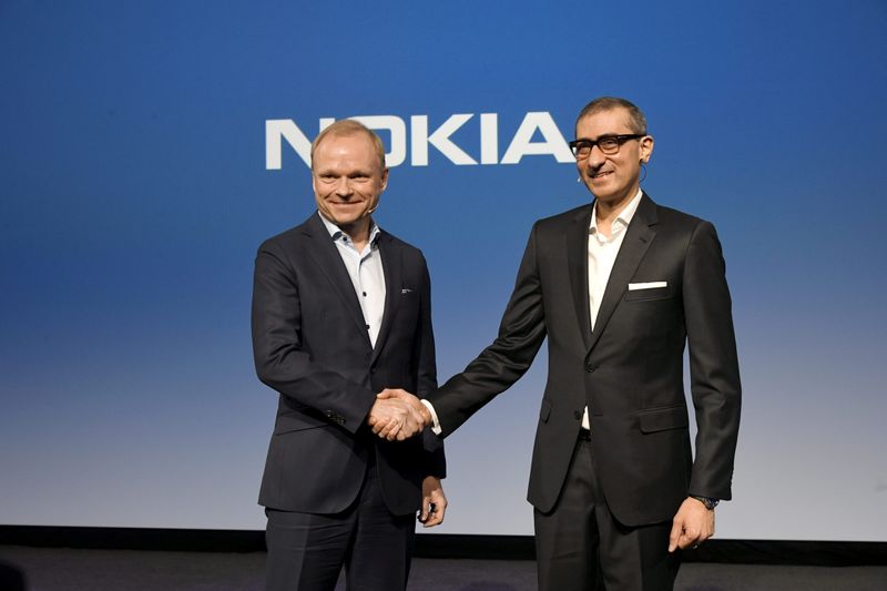 Nokia's new President and CEO Pekka Lundmark shakes hands with resigning President and CEO Rajeev Suri (R) after a news conference at the Nokia headquarters in Espoo
