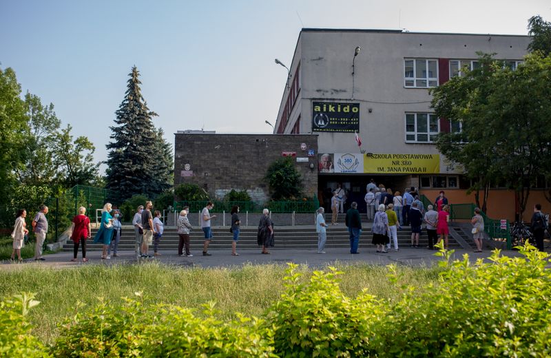 People queue outside a polling station during the presidential election in Warsaw