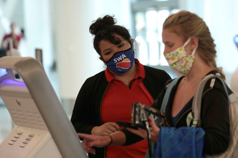 FILE PHOTO: A Southwest Airlines Co. employee wears a protective mask while assisting a passenger at Los Angeles International Airport (LAX) on an unusually empty Memorial Day weekend during the outbreak of the coronavirus disease (COVID-19) in Los Angeles