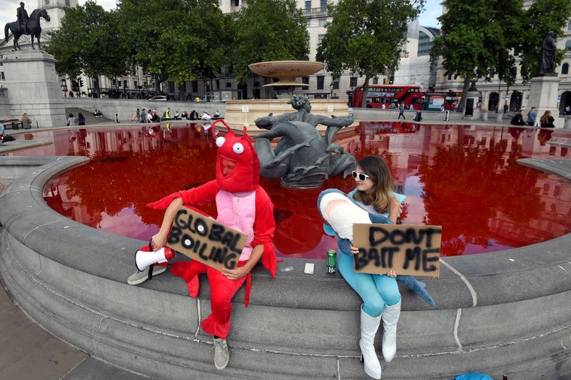 Animal rights activists hold signs as they sit at a fountain whose water was turned red after protesters poured coloured dye into the clear water, on Trafalgar Square in London