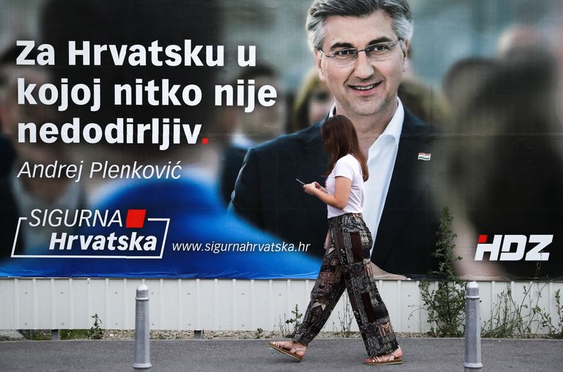 A woman walks past a banner advertising the campaign of Croatian Prime Minister and the leader of the centre-right Croatian Democratic Union (HDZ) Andrej Plenkovic in Zagreb