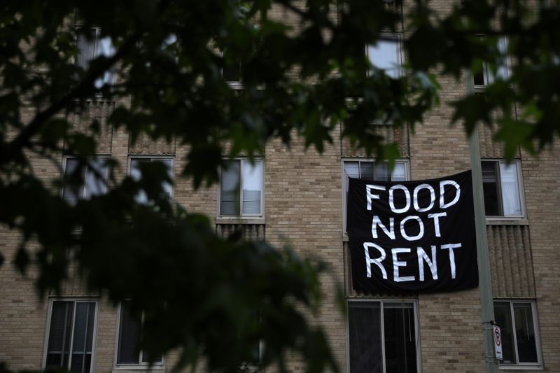 Makeshift sheets displaying messages of protest contesting the ability to pay for rent hang in the window of an apartment building in the Columbia Heights neighborhood in Washington