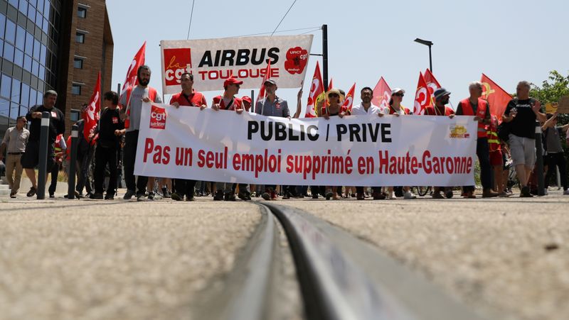 Employees of Airbus hold a banner reading 