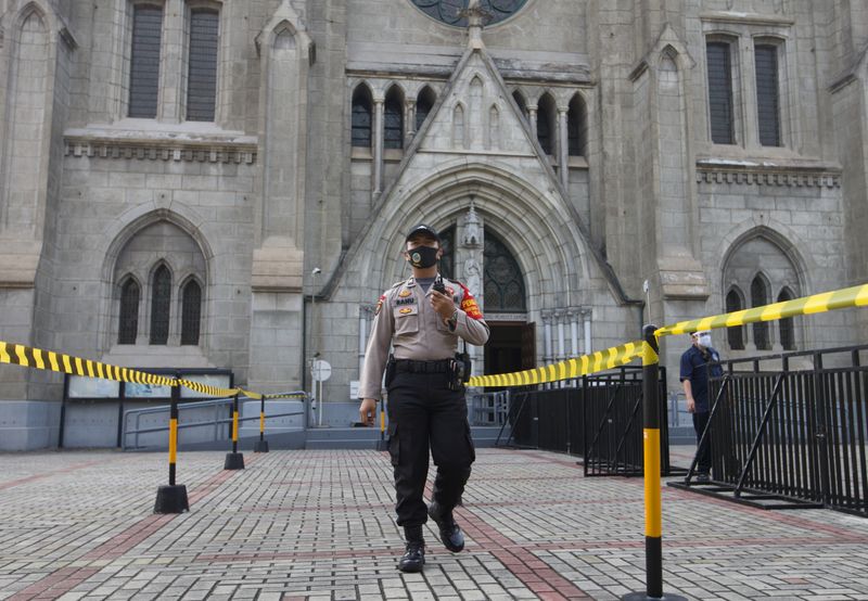 A policeman, part of a large-scale task force enforcing social restrictions amid the coronavirus disease (COVID-19) outbreak, walks with a face mask outside a church on the first day of its reopening, in Jakarta