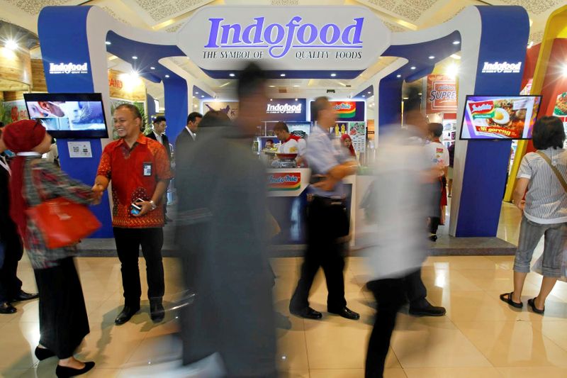 FILE PHOTO: Visitors walk past the booth of Indonesian food giant Pt. Indofood Sukses Makmur at a trade exhibition in Jakarta,