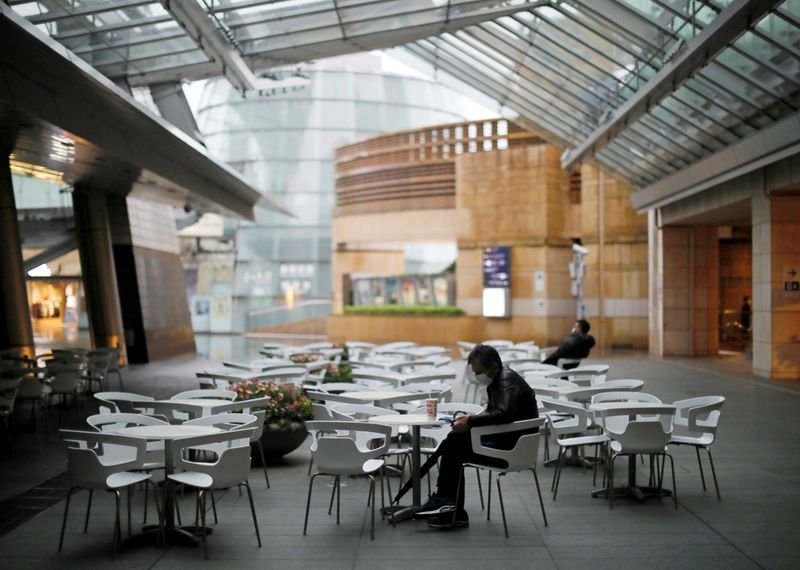 People wearing protective face masks, following an outbreak of the coronavirus disease (COVID-19), takes a rest next to almost empty seats of a cafe and restaurant at the Roppongi Hills complex in Tokyo