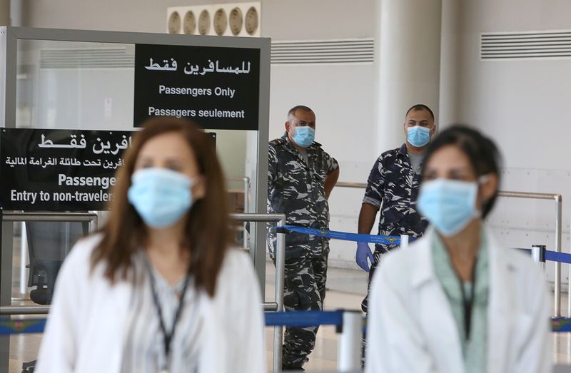 Health workers and members of internal security forces wearing face masks stand inside Beirut international airport