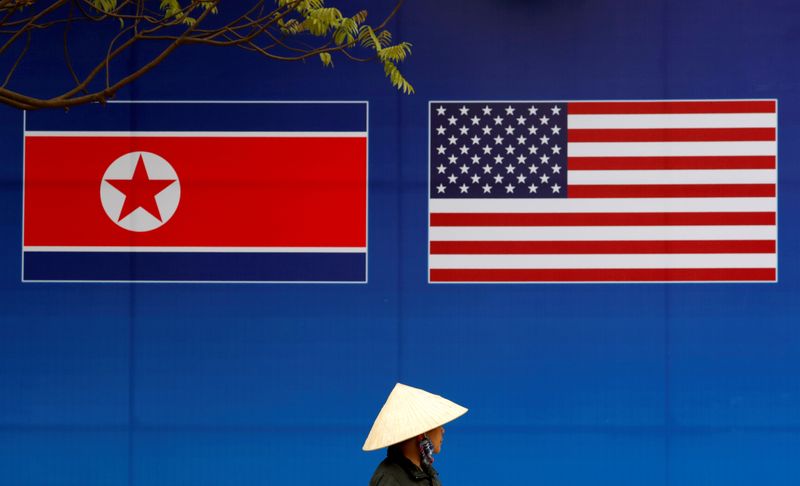 A person walks past a banner showing North Korean and U.S. flags ahead of the North Korea-U.S. summit in Hanoi