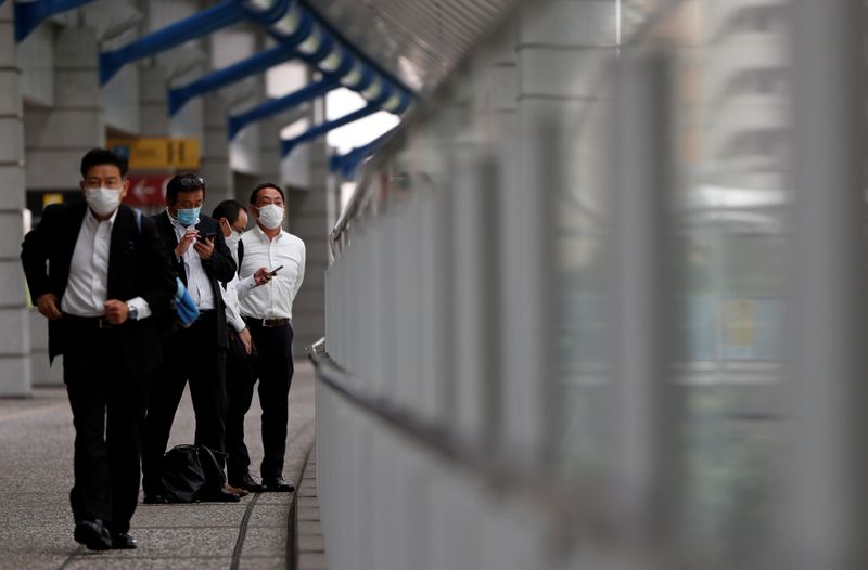 Businessmen wearing protective face masks are seen on a pedestrian bridge in a business district in Tokyo