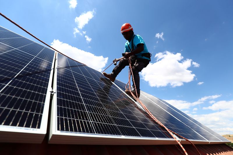 Kauahou, a worker of the installation company Alromar, sets up solar panels on the roof of a home in Colmenar Viejo